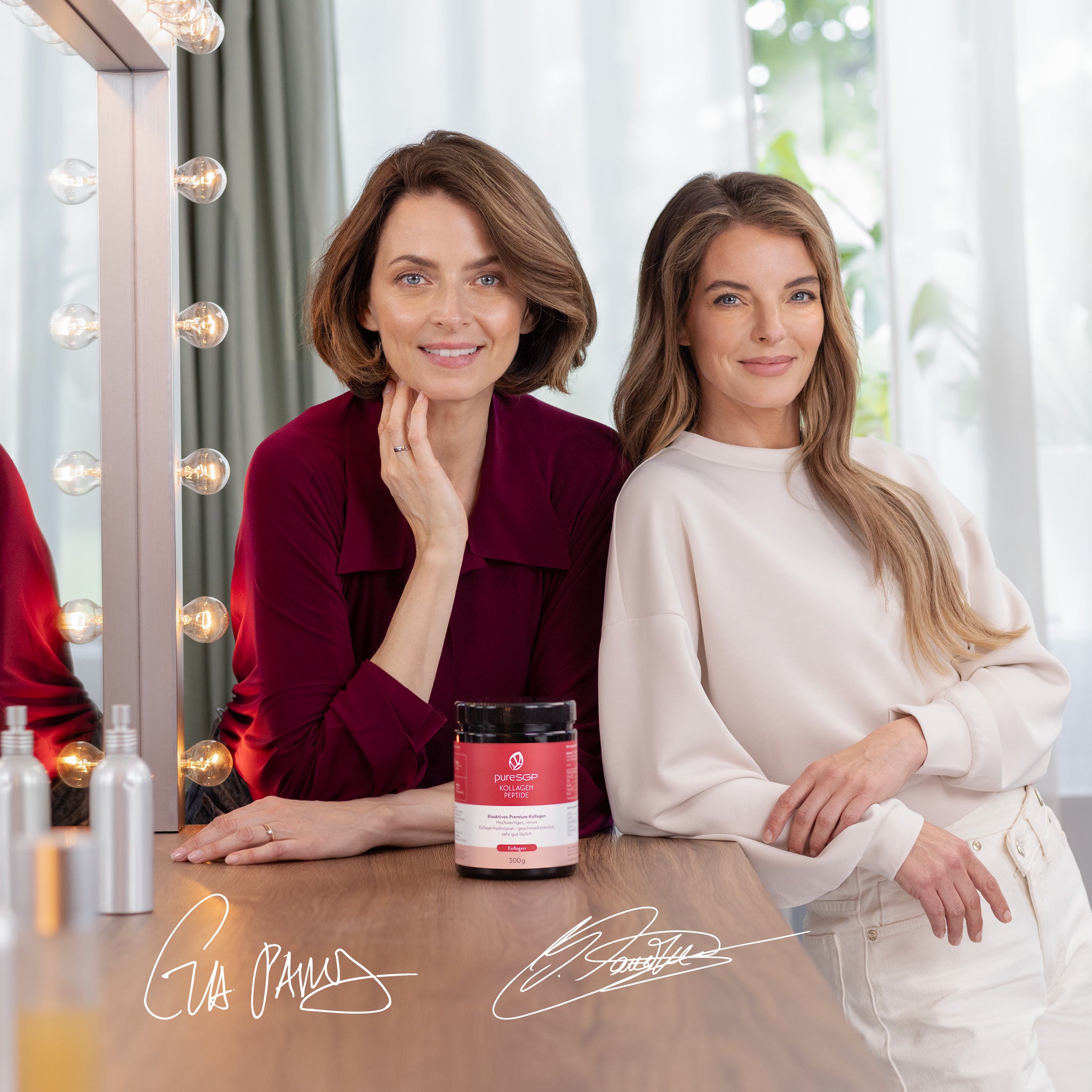 Das Model Eva Padberg und die Sängerin Yvonne Catterfield sitzen an einem Schminktisch neben einem beleuchteten Spiegel; im Vordergrund steht eine Dose „pureSGP Kollagen Peptide“ (300 g).